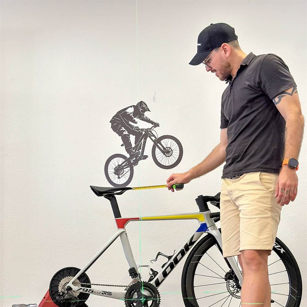 Victor Castelo Branco a medir a altura do selim com fita métrica, com a linha laser a passar pelo eixo do pedaleiro, no estúdio em Oeiras